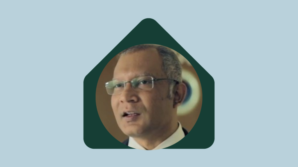 Headshot of a man with glasses smiling inside of a green house shape on a blue background