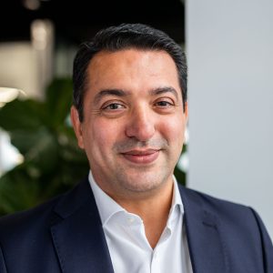 Headshot of man in blazer and shirt smiling