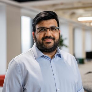 Headshot of man in button shirt with glasses smiling